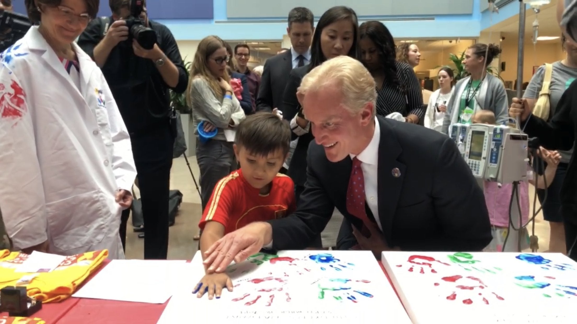 Kevin Reilly helps a child make handprint with paint.