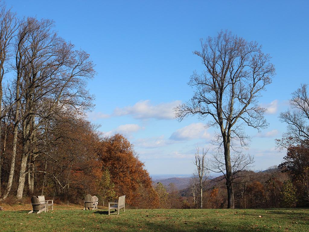 The Blue Ridge Mountains in the distance, seen through the trees on a sunny fall day from the lawn of the Calcagnini Contemplative Center