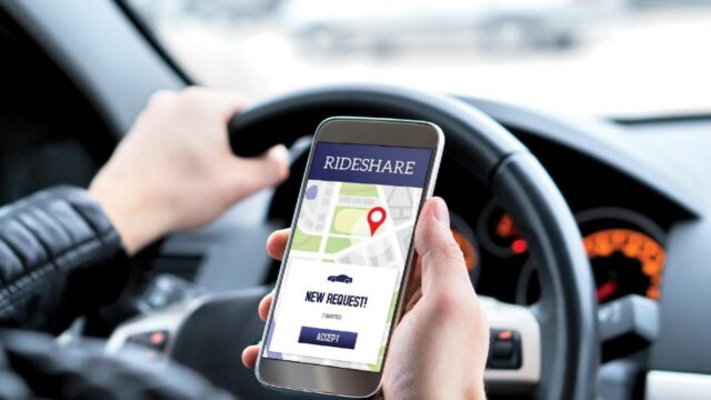 uber driver holding phone with rideshare app open