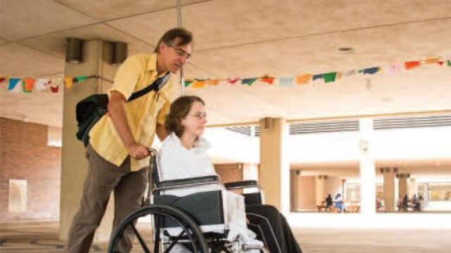 man pushing woman in wheelchair