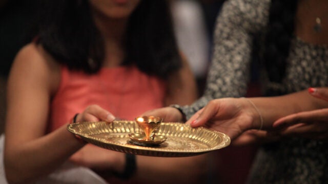 Students sing bhajans (hymns) while encircling the Icons with a ghee-lamp in the Hindu ritual of aarti, which asks God to bless the devotee’s heart and mind with love and compassion.
