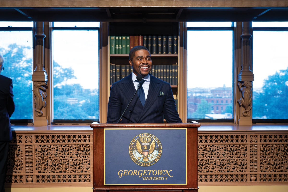 a man stands at a podium between windows