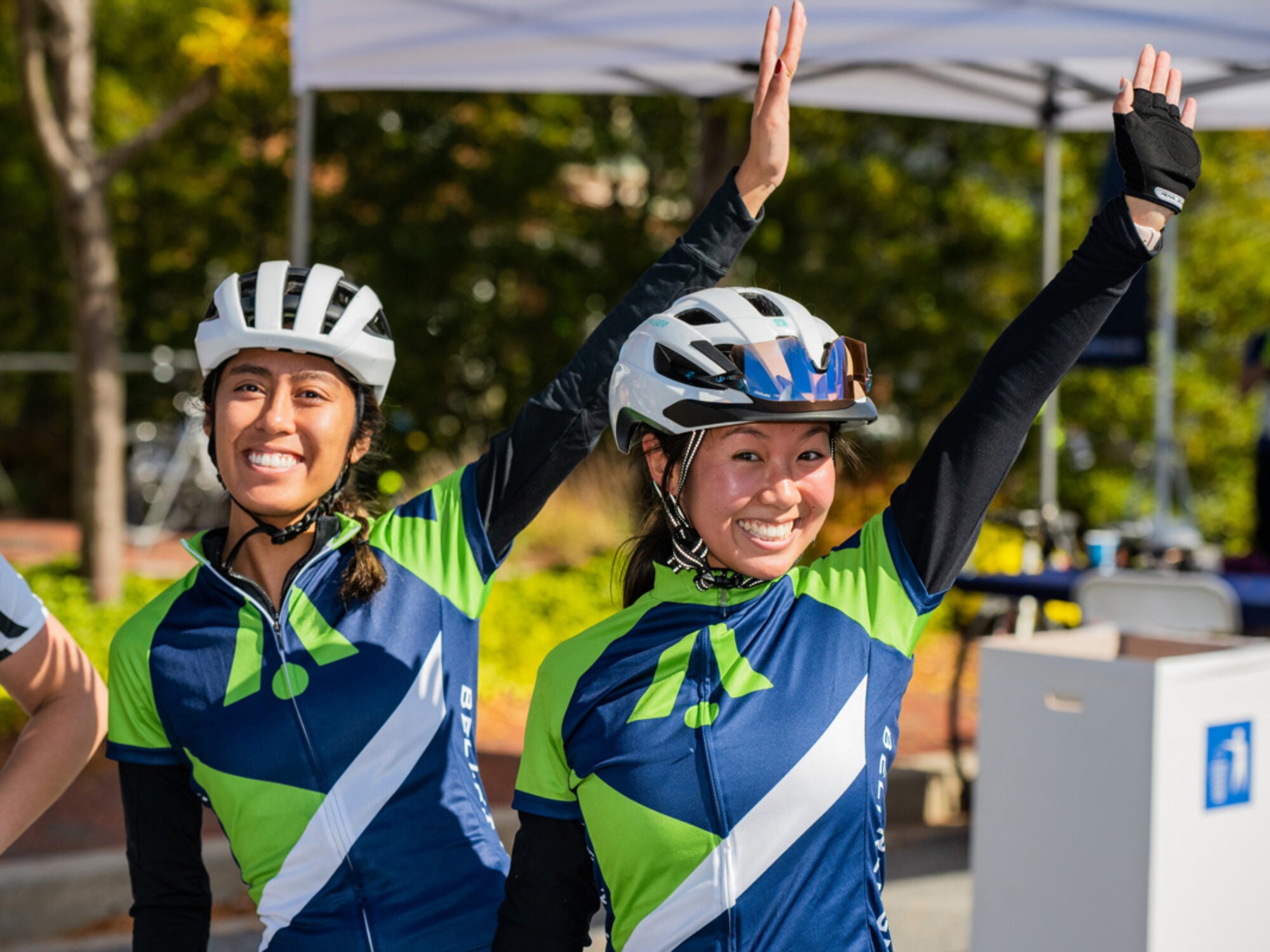 two riders waving their arms smiling