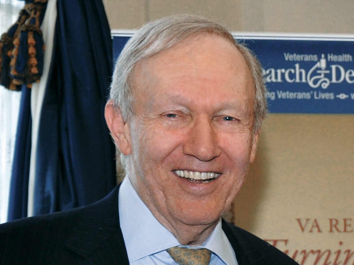 A man in a suit and tie smiles at the camera