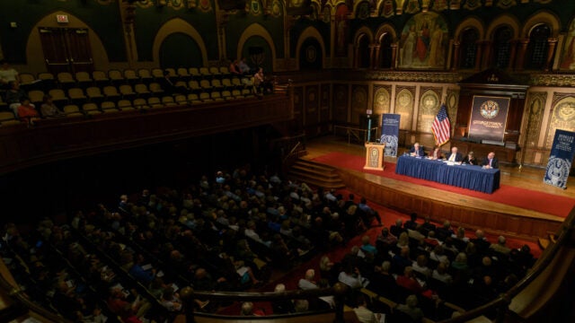 an audience in a chapel looks at a panel of speakers
