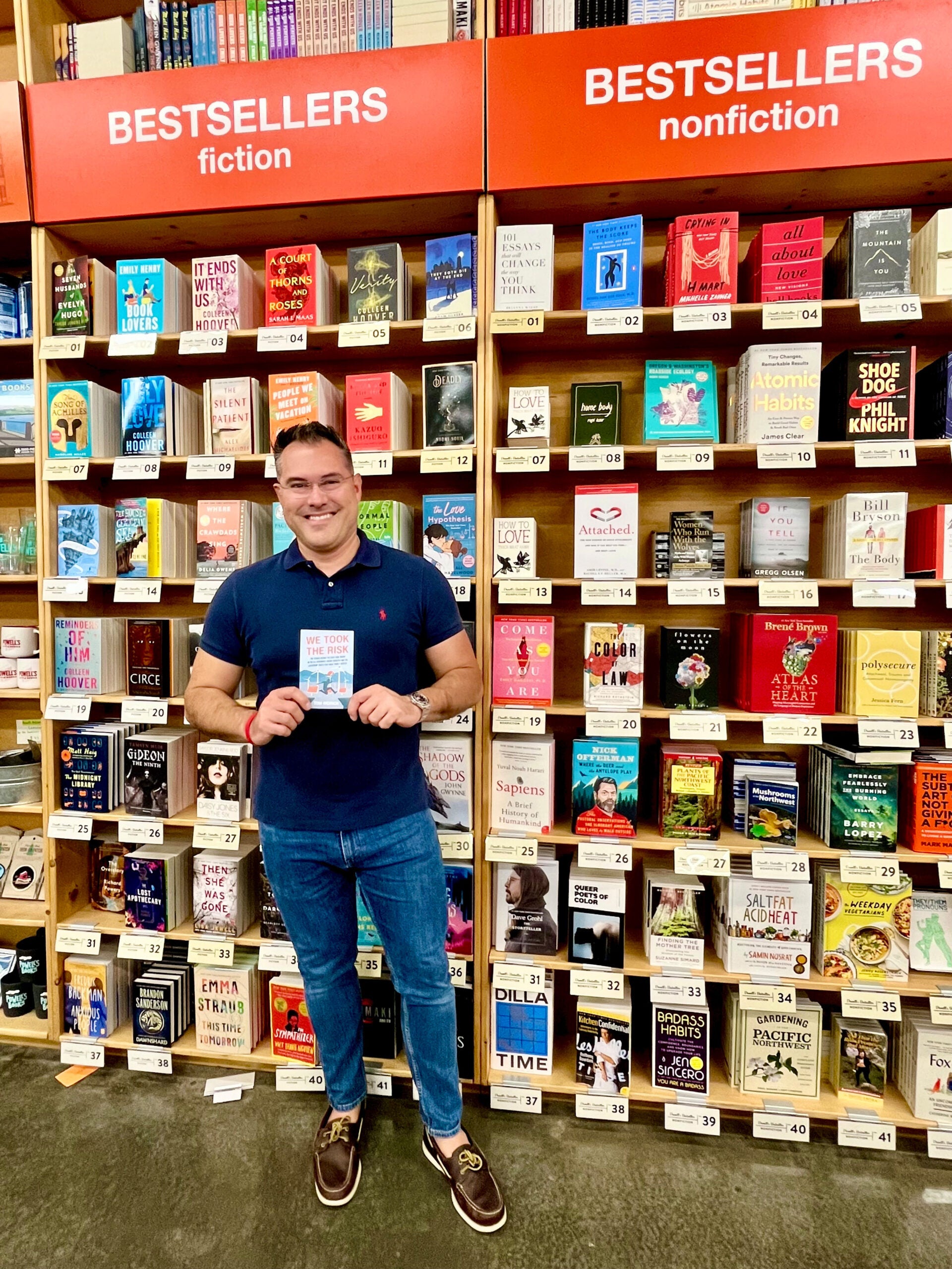 a man stands with a book in front of a book shelf display