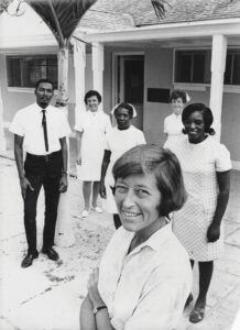 a woman stands outside a building with other staff