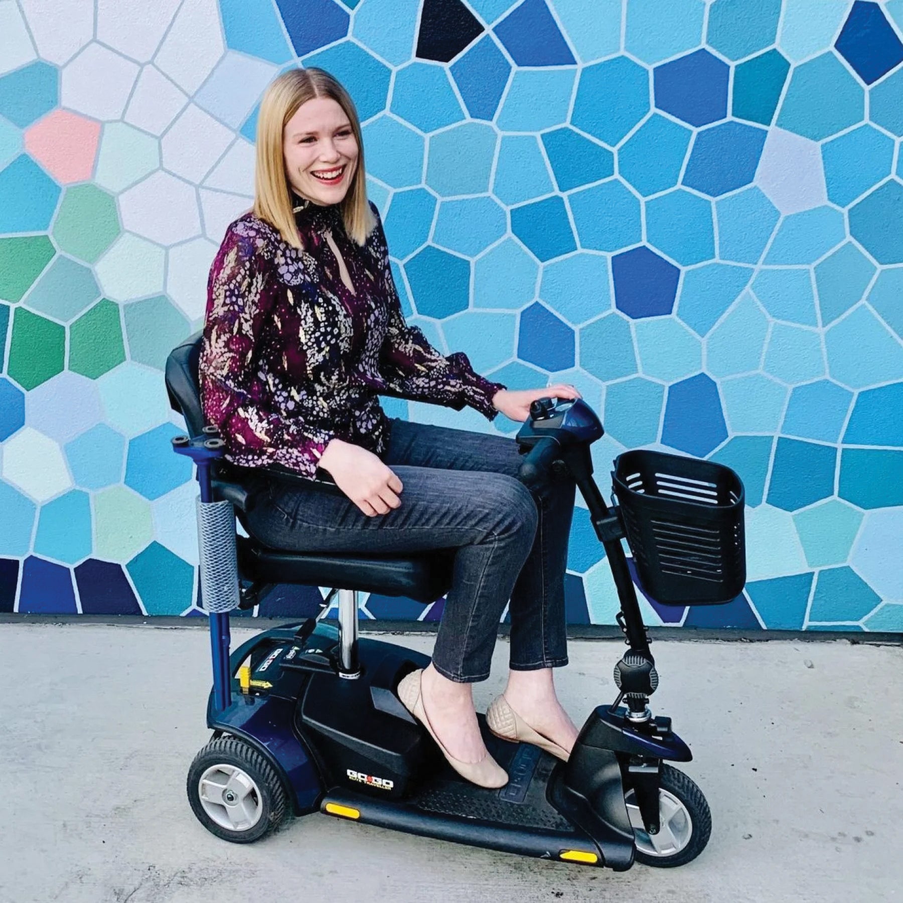 a woman who uses a wheelchair is in front of a mosaic