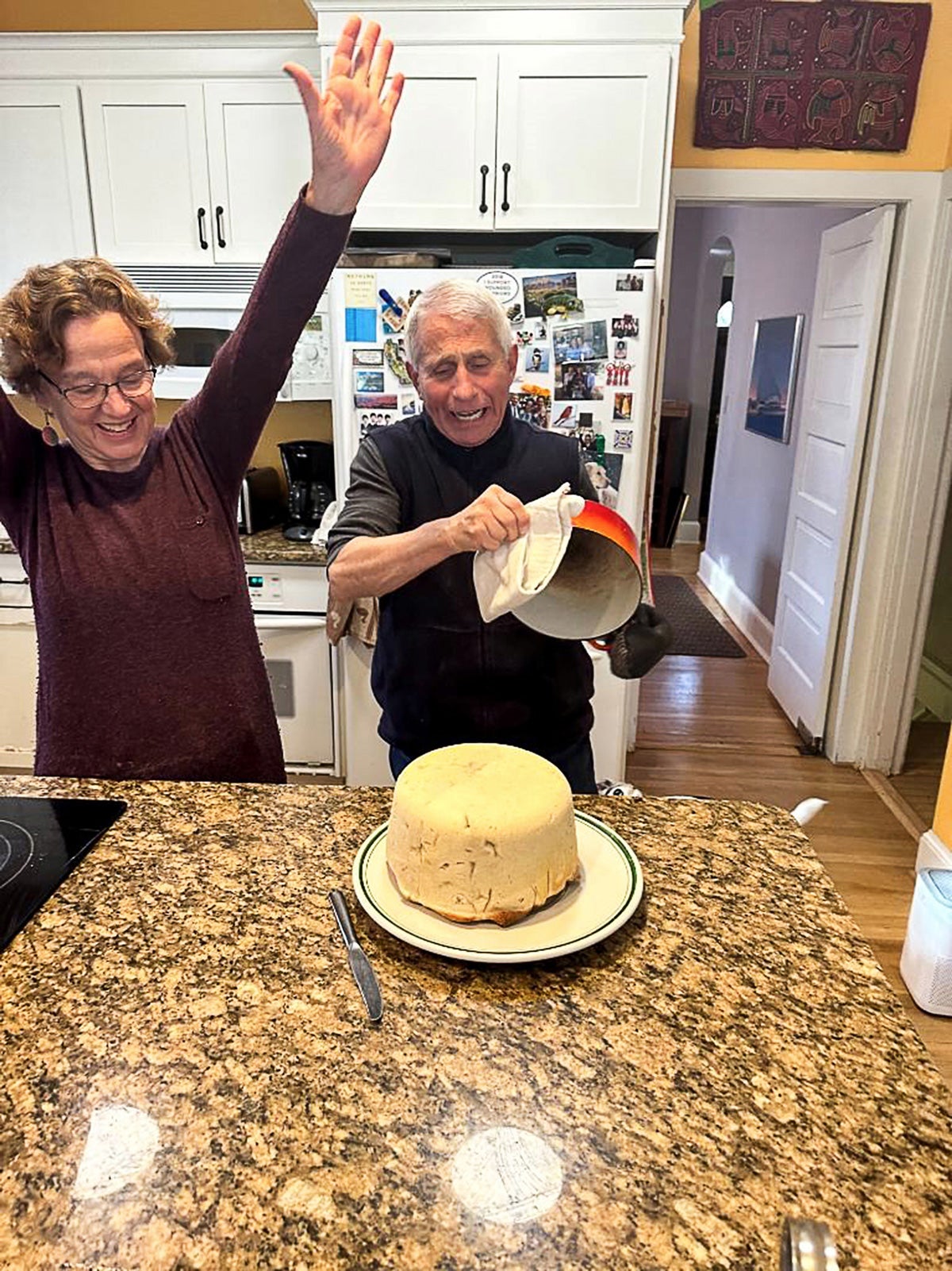 a man and a woman transfer a cake to a plate 