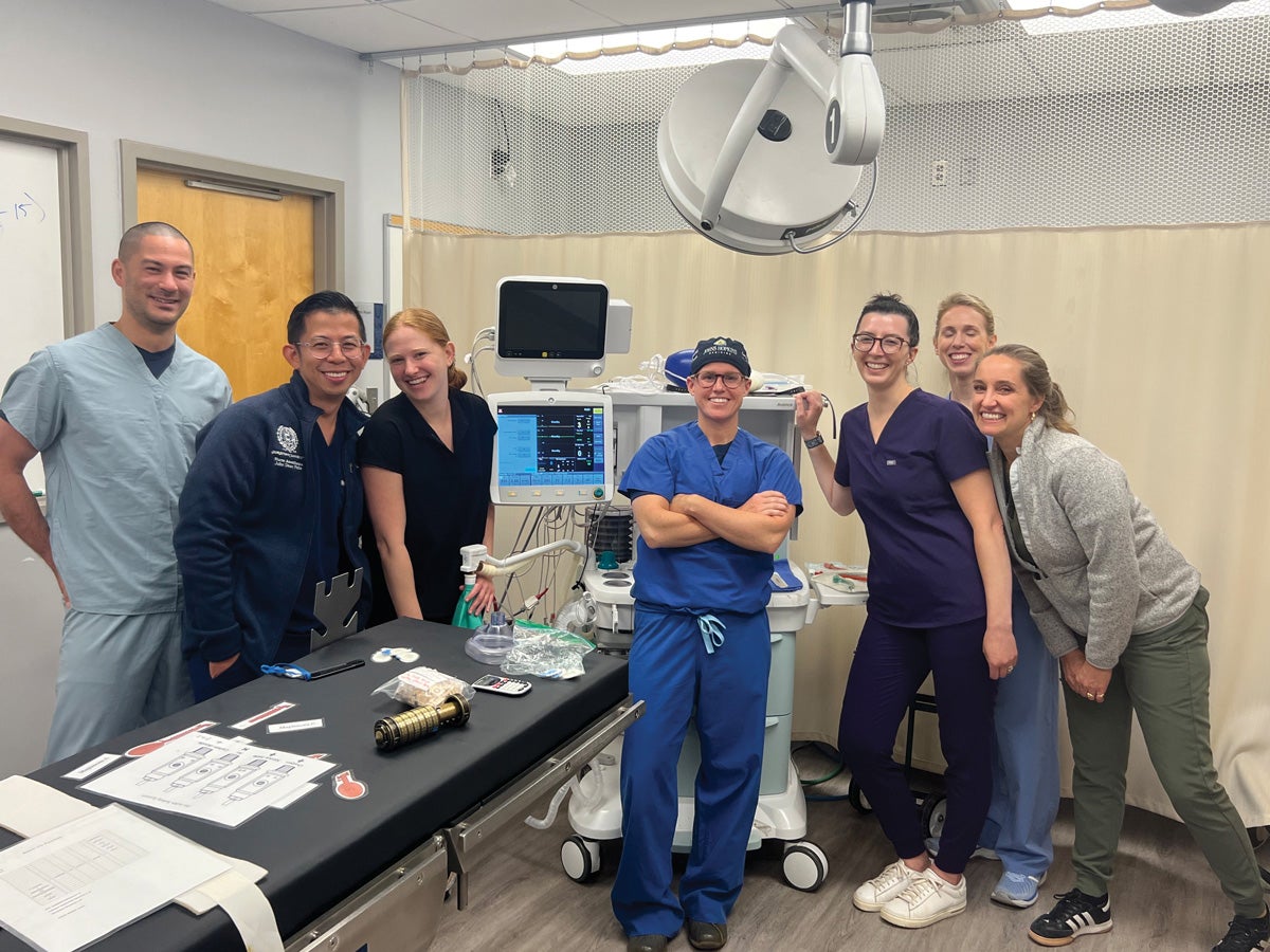 seven nursing students in medical scrubs smile together in a medical room