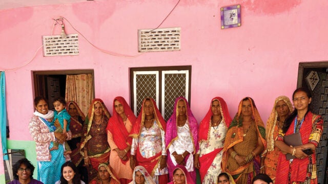 women in traditional Indian saris stand in a pink room