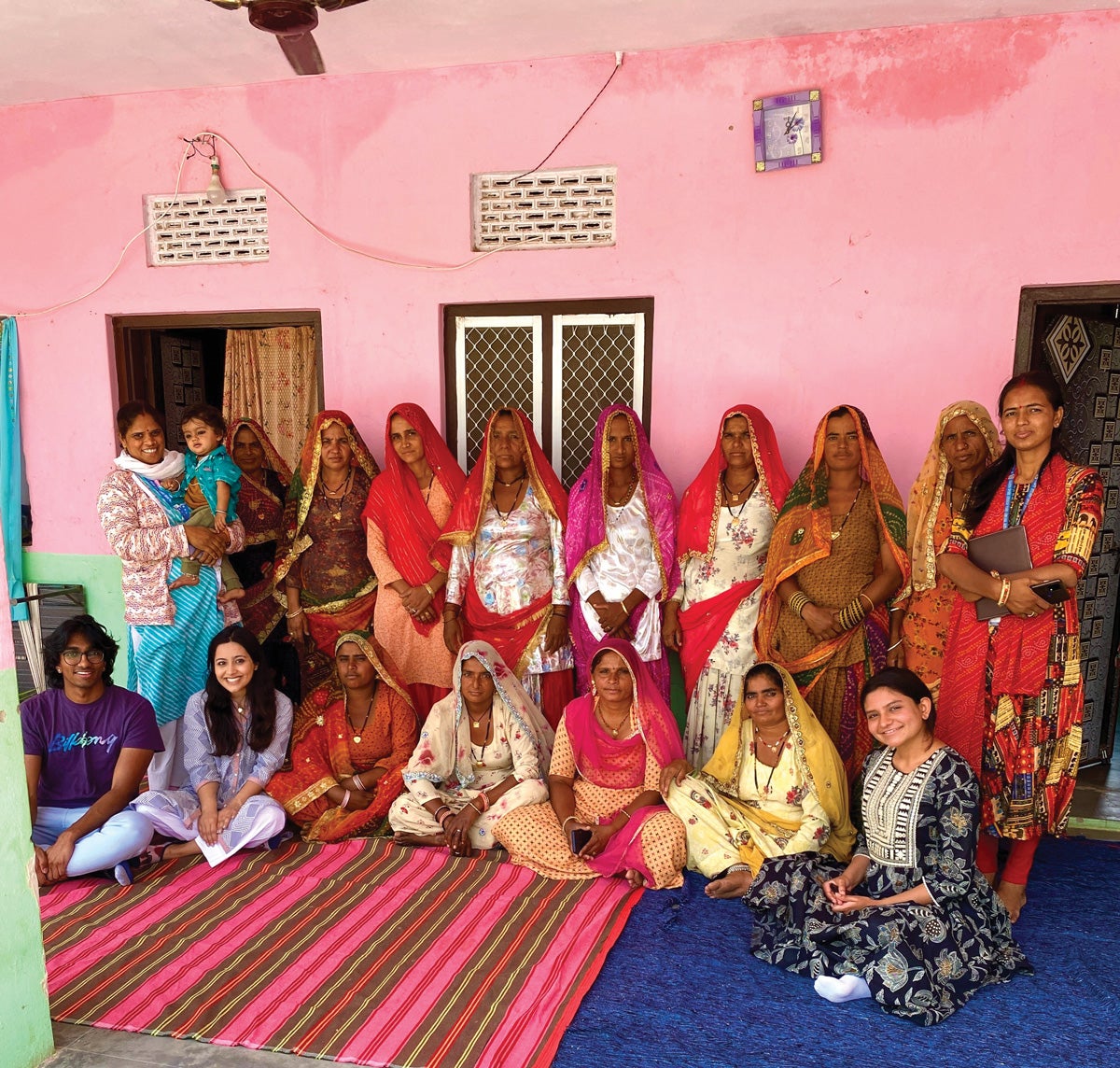 women in traditional Indian saris stand in a pink room