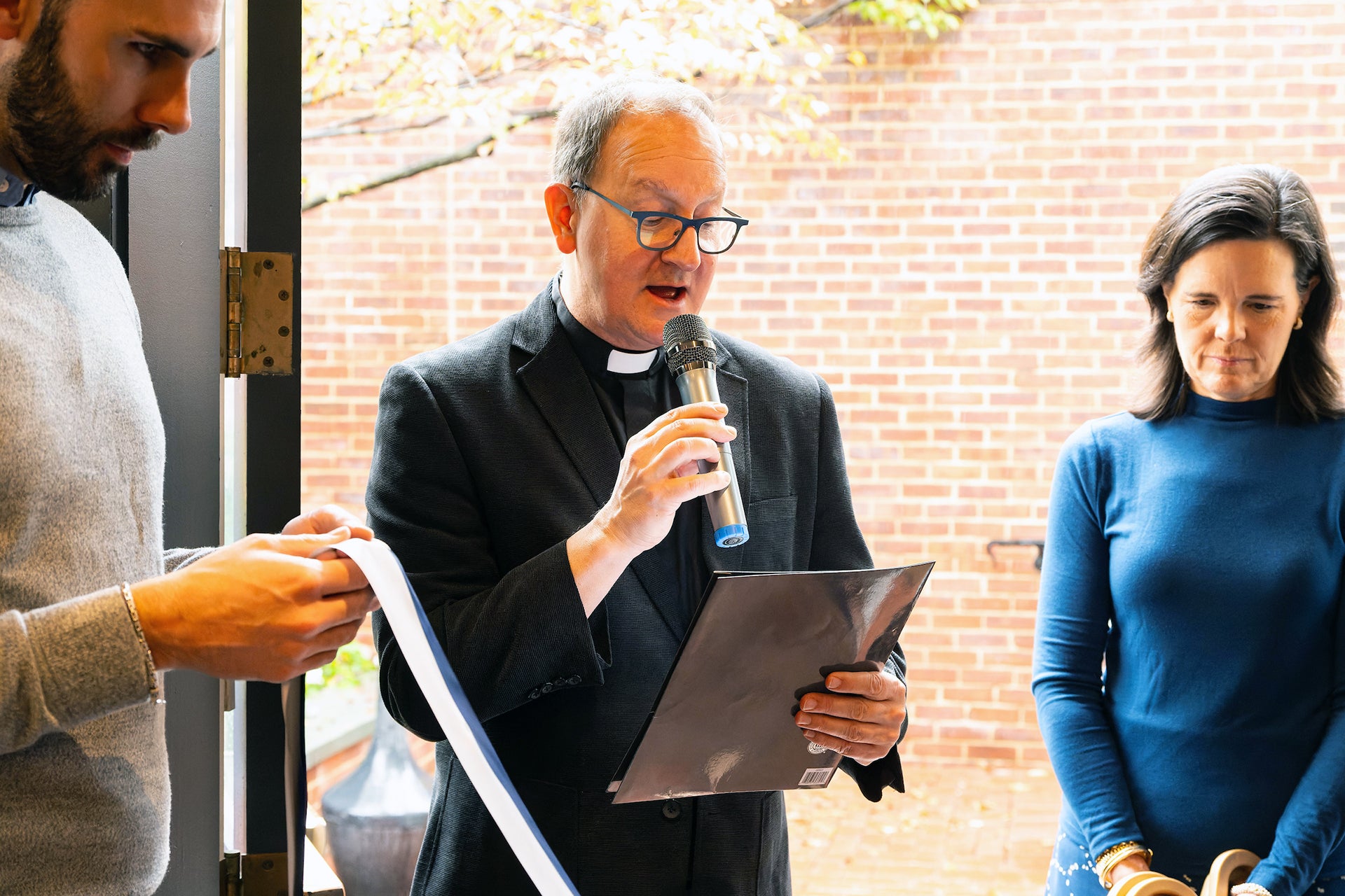 a priest and two other people at the opening ribbon-cutting ceremony