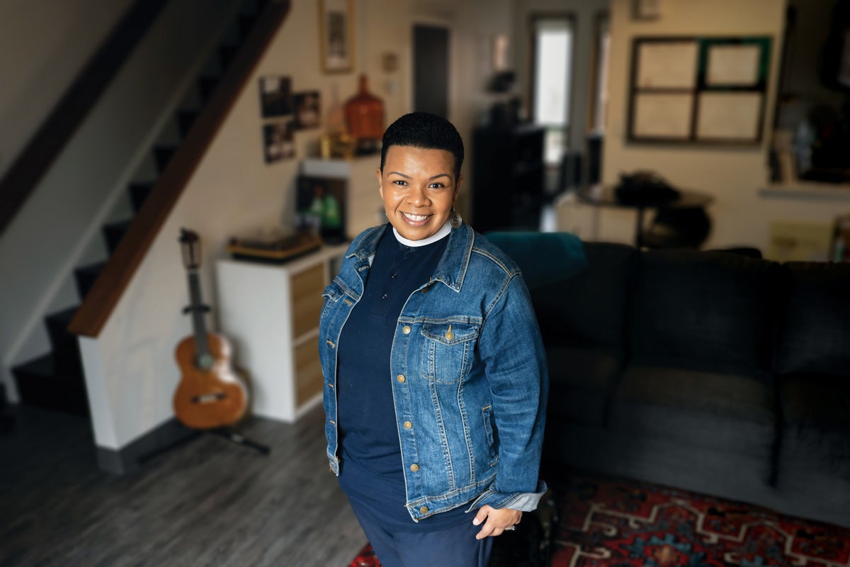 a woman in a denim jacket and navy clothes stands in a house