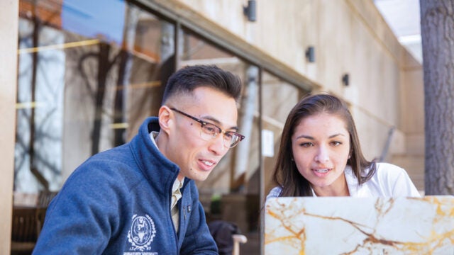students studying with each other on laptops