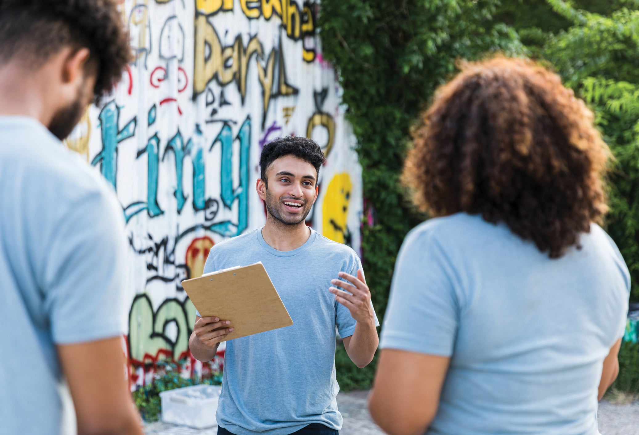 The young adult male graffiti clean-up organizer explains the project for the weekend.