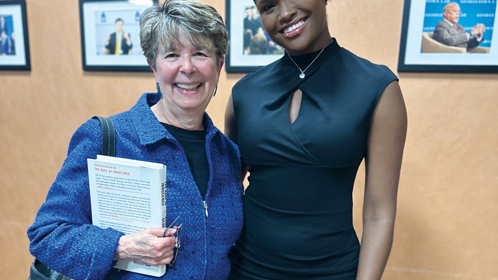 two women - one in a black dress and the other in a blue sweater - stand with each other