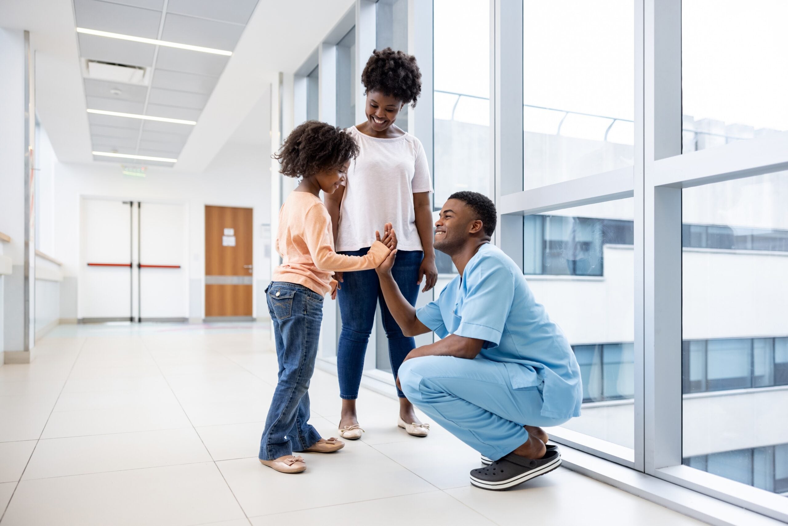 Happy African American girl giving a high-five to a male nurse at the hospital - healthcare and medicine concepts