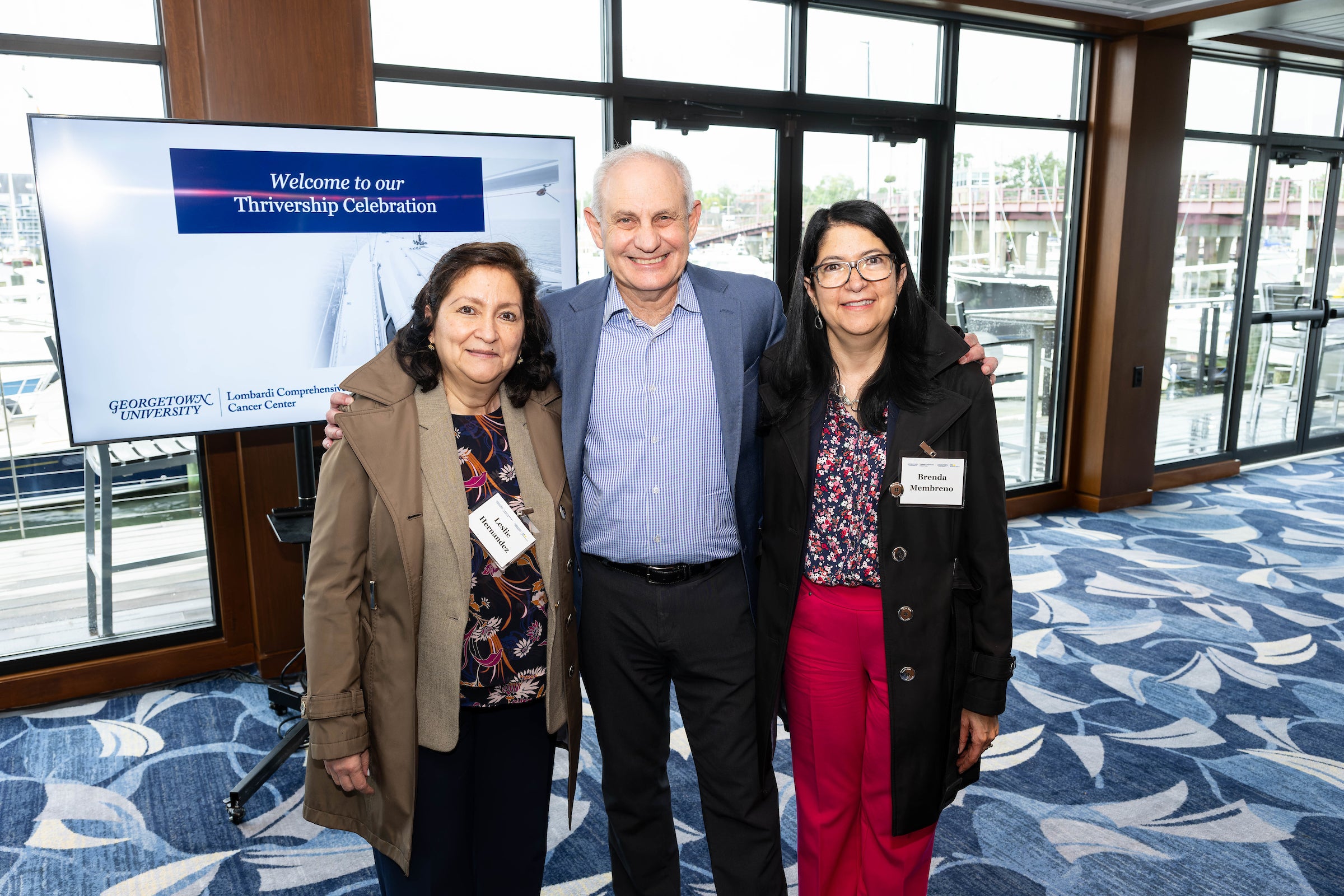 three people stand in front of a display screen