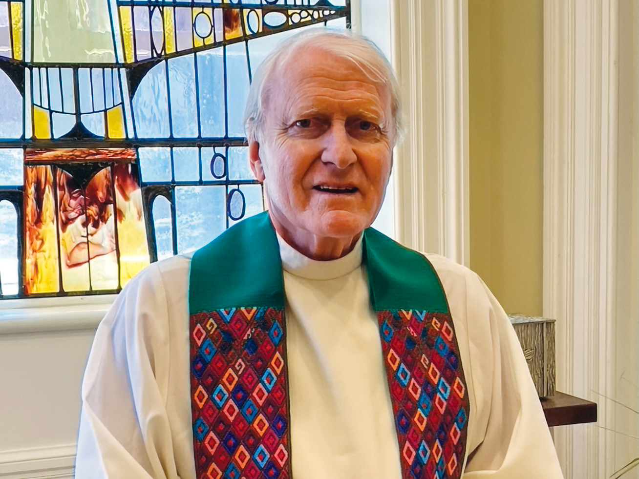 a man in religious clothing in front of a stained glass window