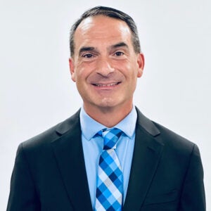 a man in a charcoal suit with a light blue striped tie