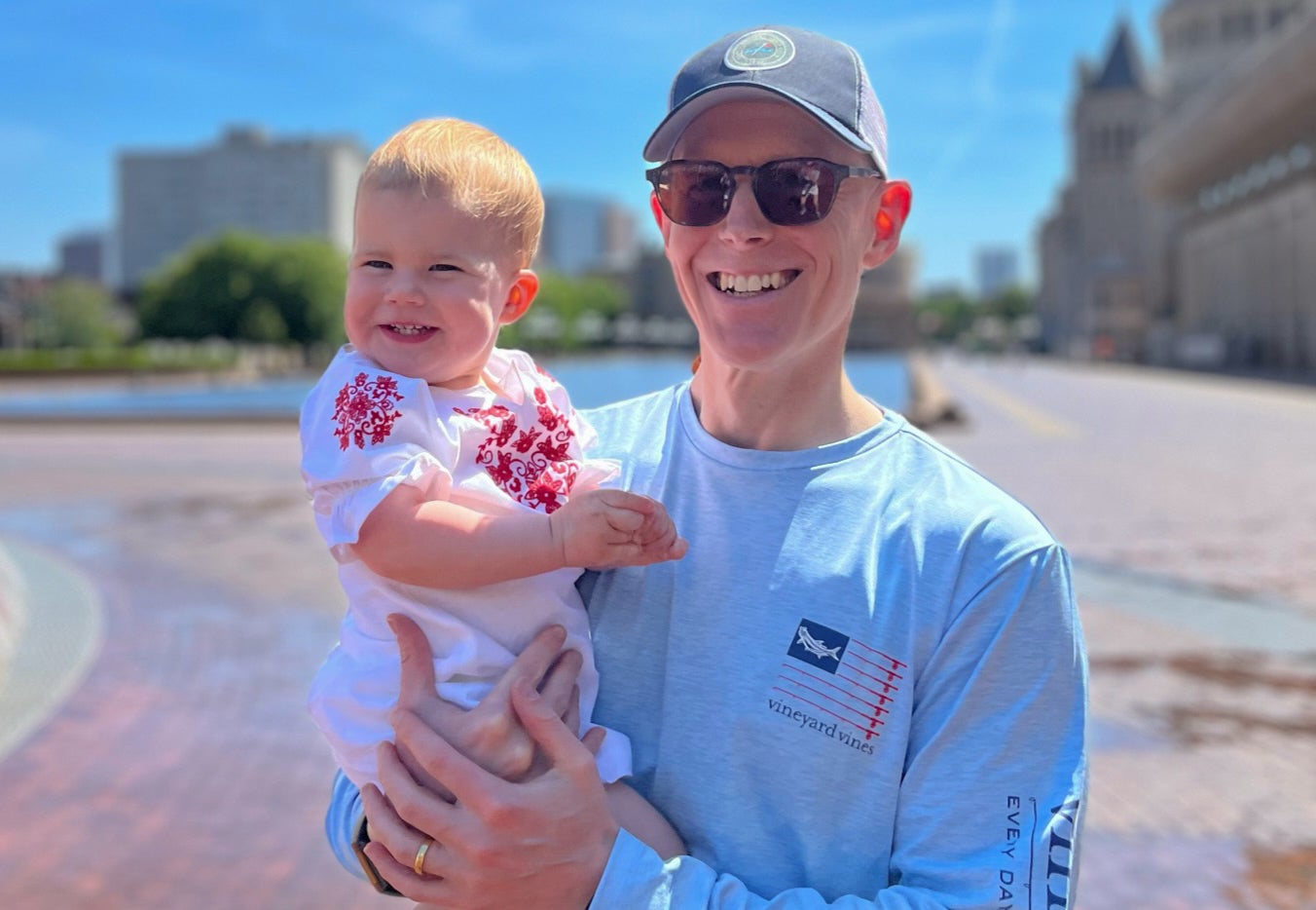 a man holding a toddler while in the sunshine