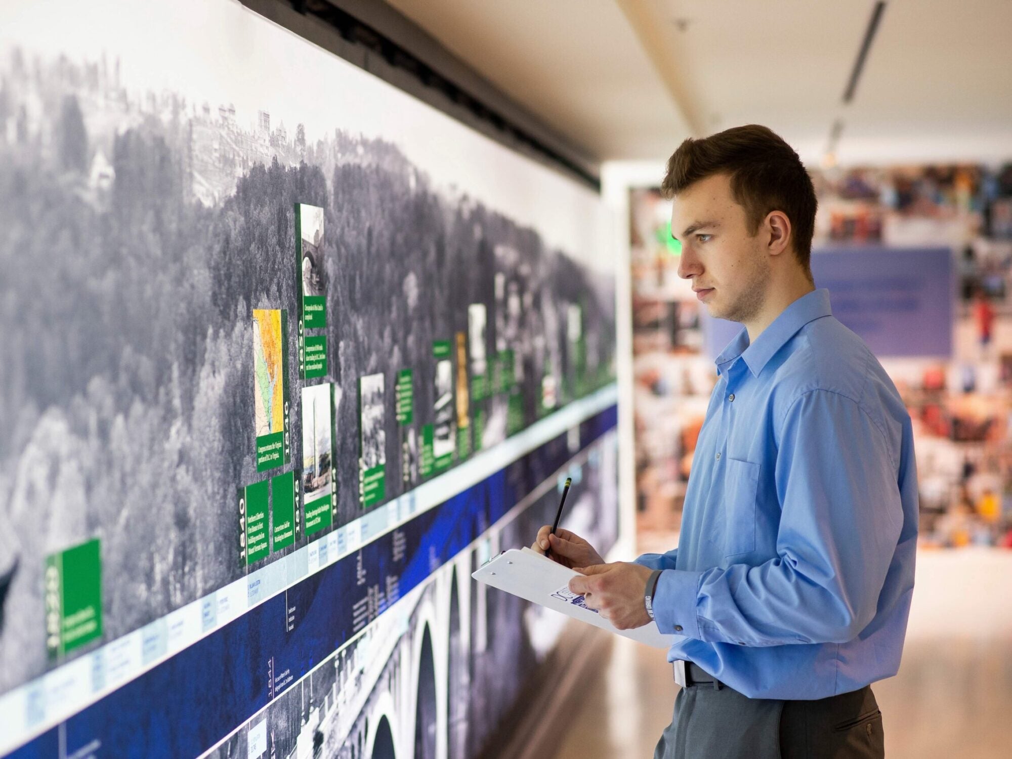 student taking notes next to big screen