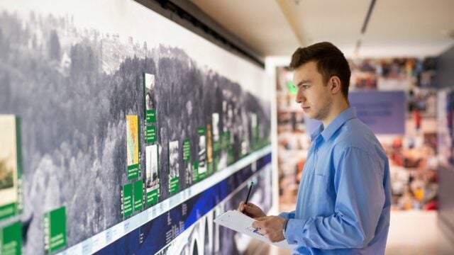 student taking notes next to big screen