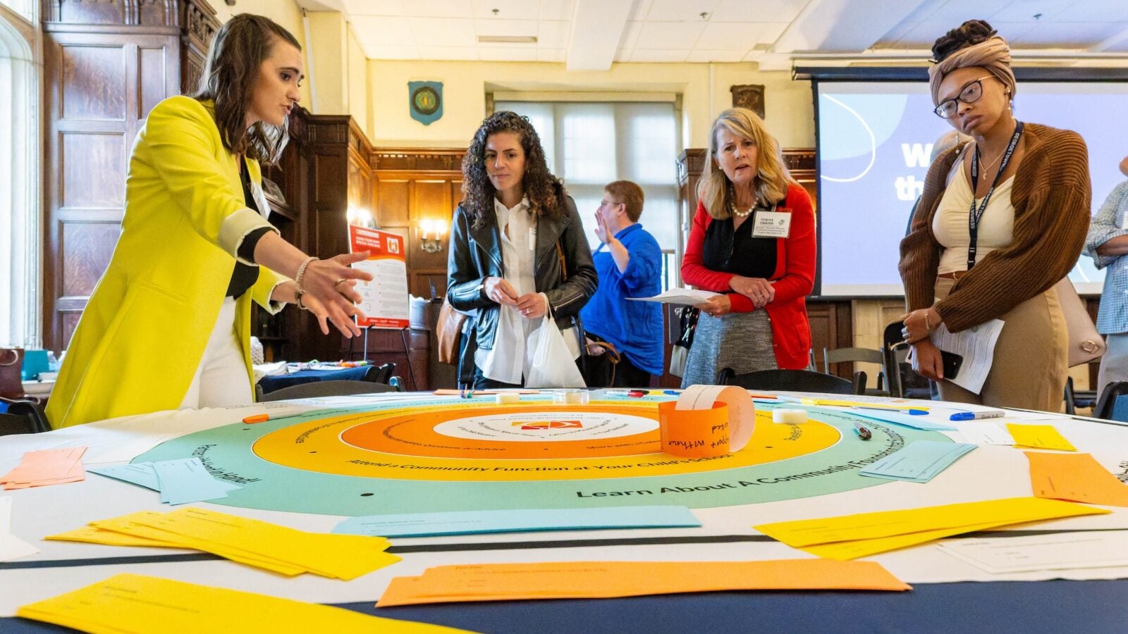 The Innovation Hub at the Thrive Center, which offers 12-week fall and spring fellowships, held an inaugural Solutions Fair highlighting the work of its Spring 2025 fellows. Here, a diagram at the Hand in Hand Parenting display explains the program’s structural model to support parents and caregivers.