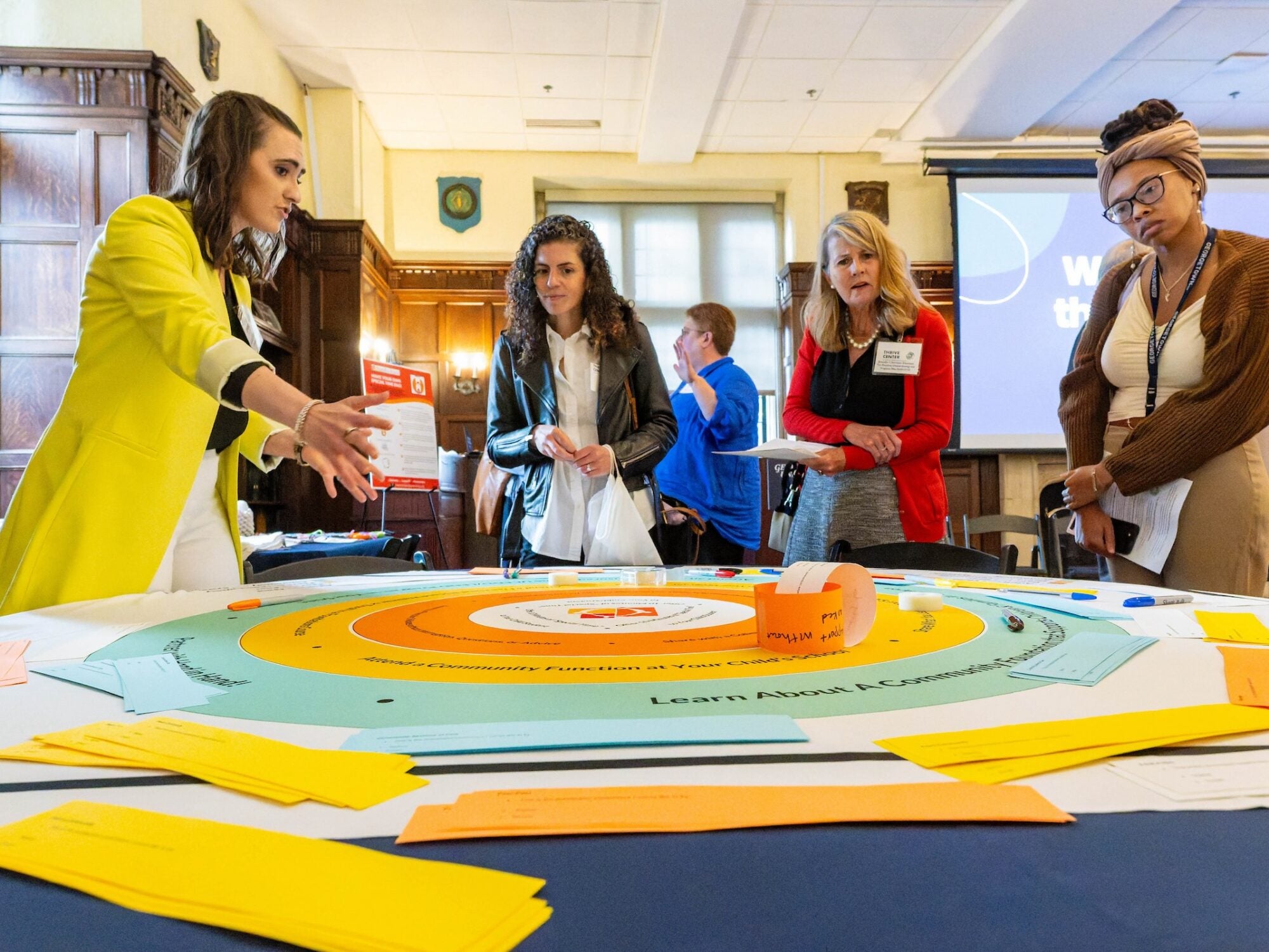 The Innovation Hub at the Thrive Center, which offers 12-week fall and spring fellowships, held an inaugural Solutions Fair highlighting the work of its Spring 2025 fellows. Here, a diagram at the Hand in Hand Parenting display explains the program’s structural model to support parents and caregivers.