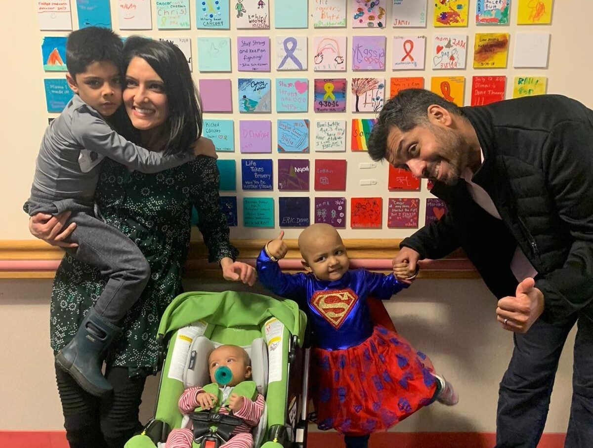 a family with two parents, two small children and a baby in a carseat