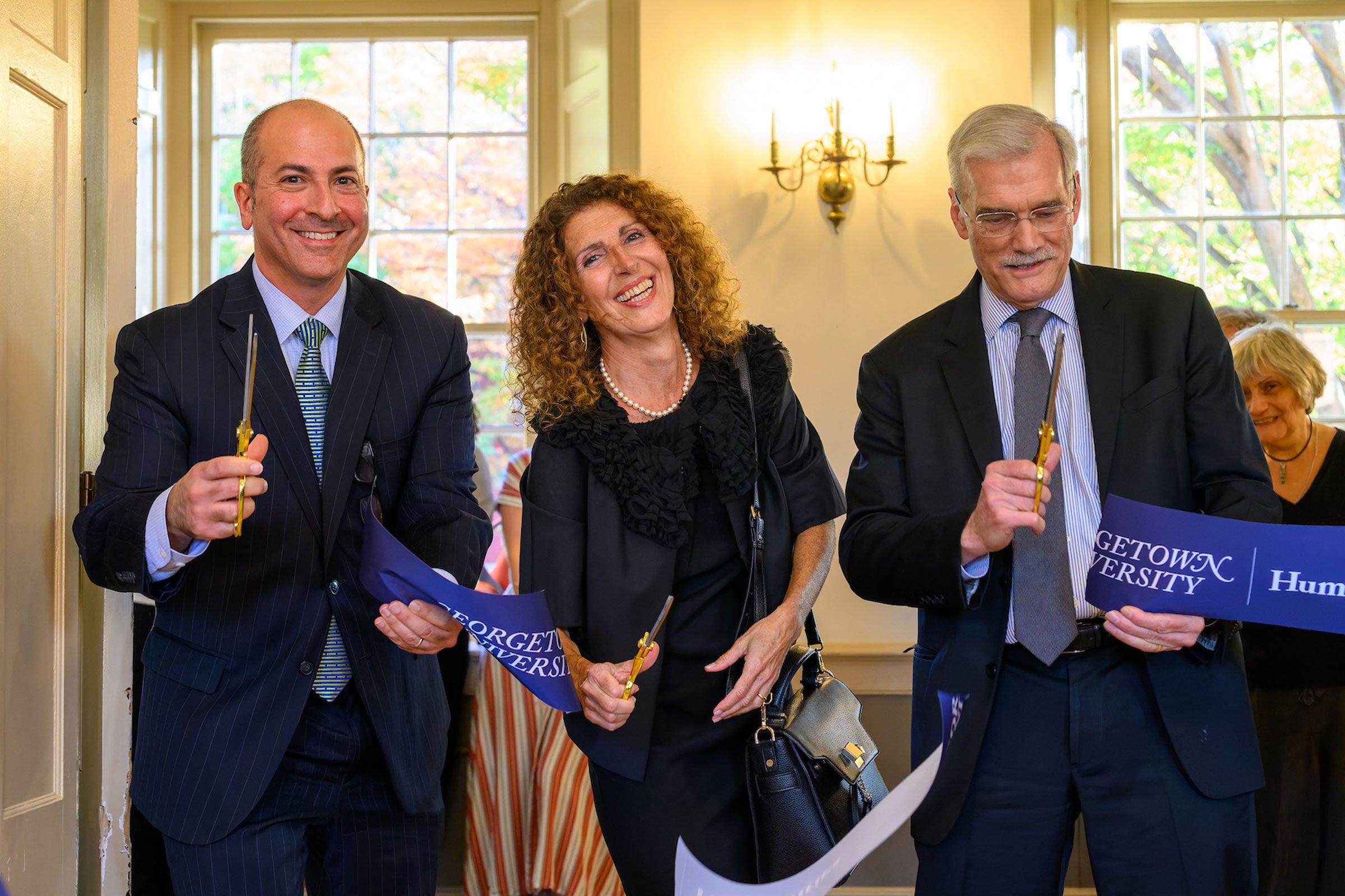three people cut a large ribbon inside of a doorway
