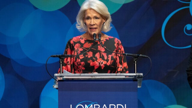 a woman in a black and red dress gives a speech at the Lombardi Gala podium