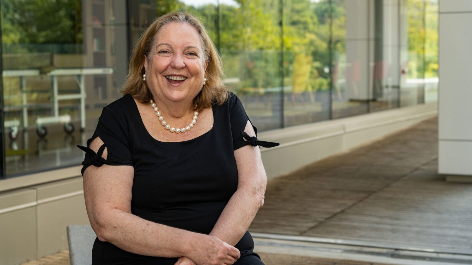 a woman in a black dress sits outside a building