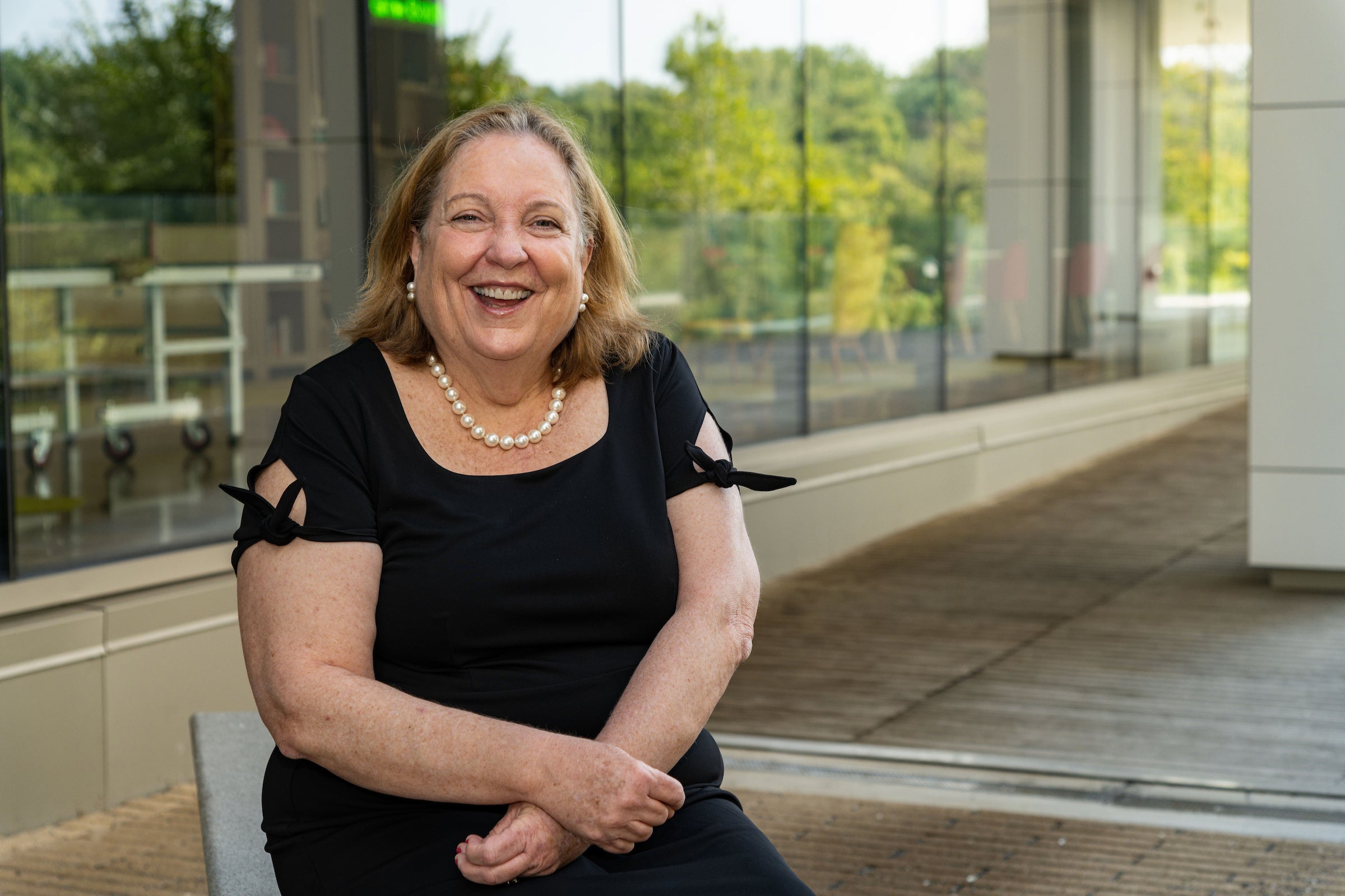 a woman in a black dress sits outside a building