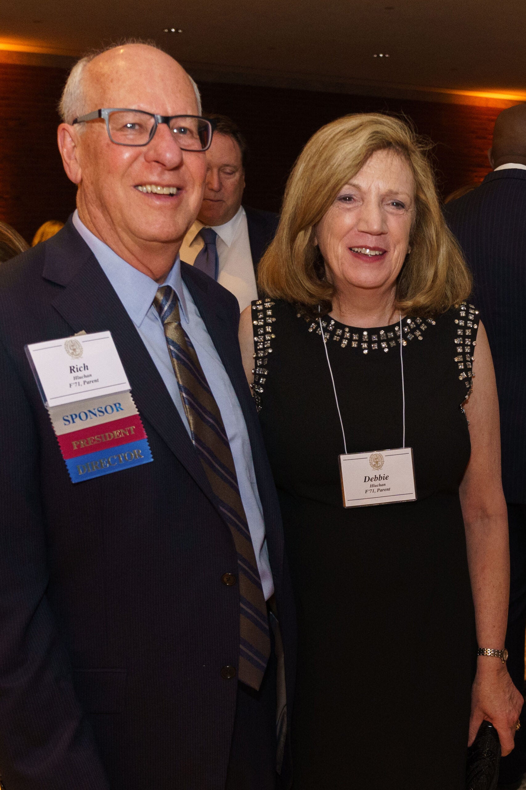 a man and a woman in business attire with nametags pose together