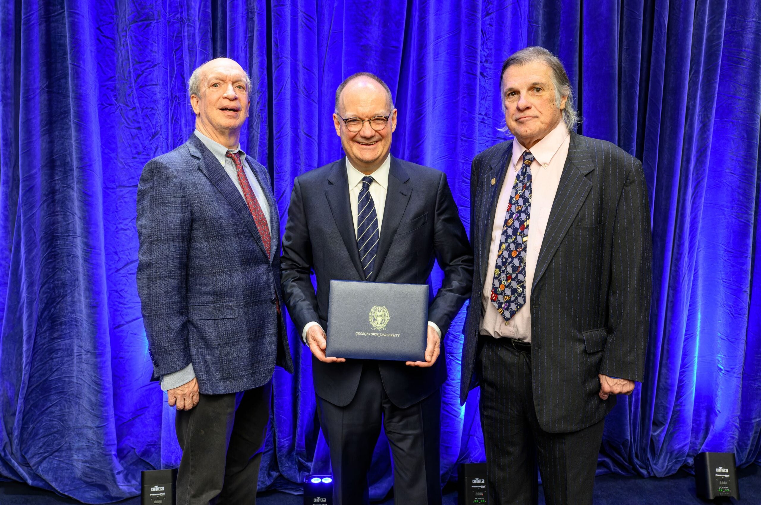 three men stand together holding an award plaque