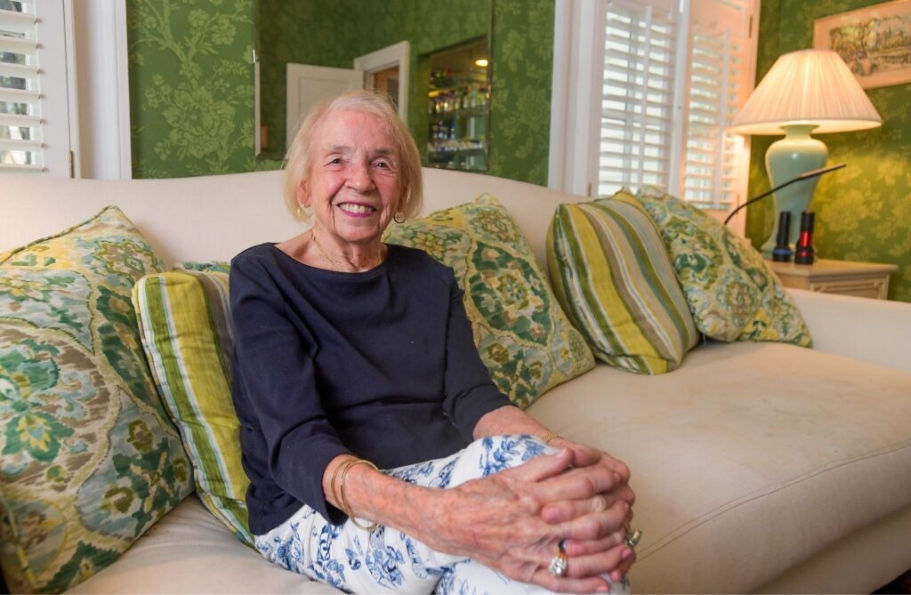 a smiling woman sits on a couch in a living room 