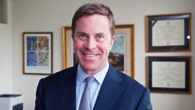 Photo of Paul O'Neill in front of a wall with photos.