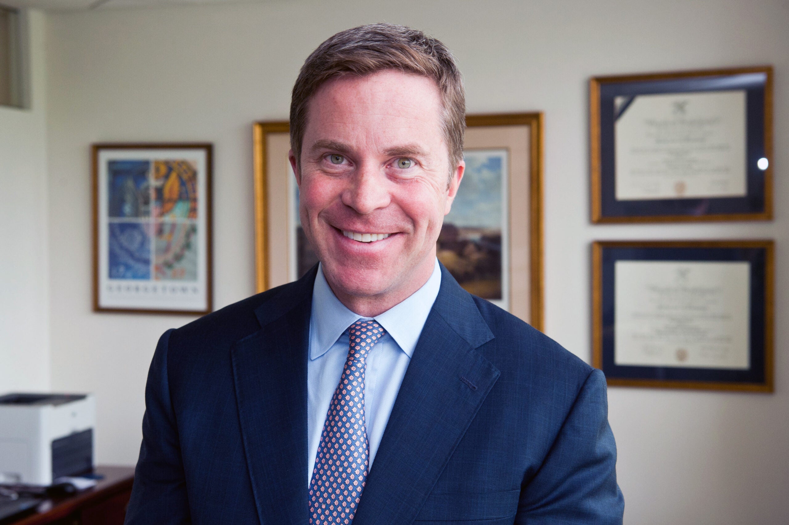 Photo of Paul O'Neill in front of a wall with photos.