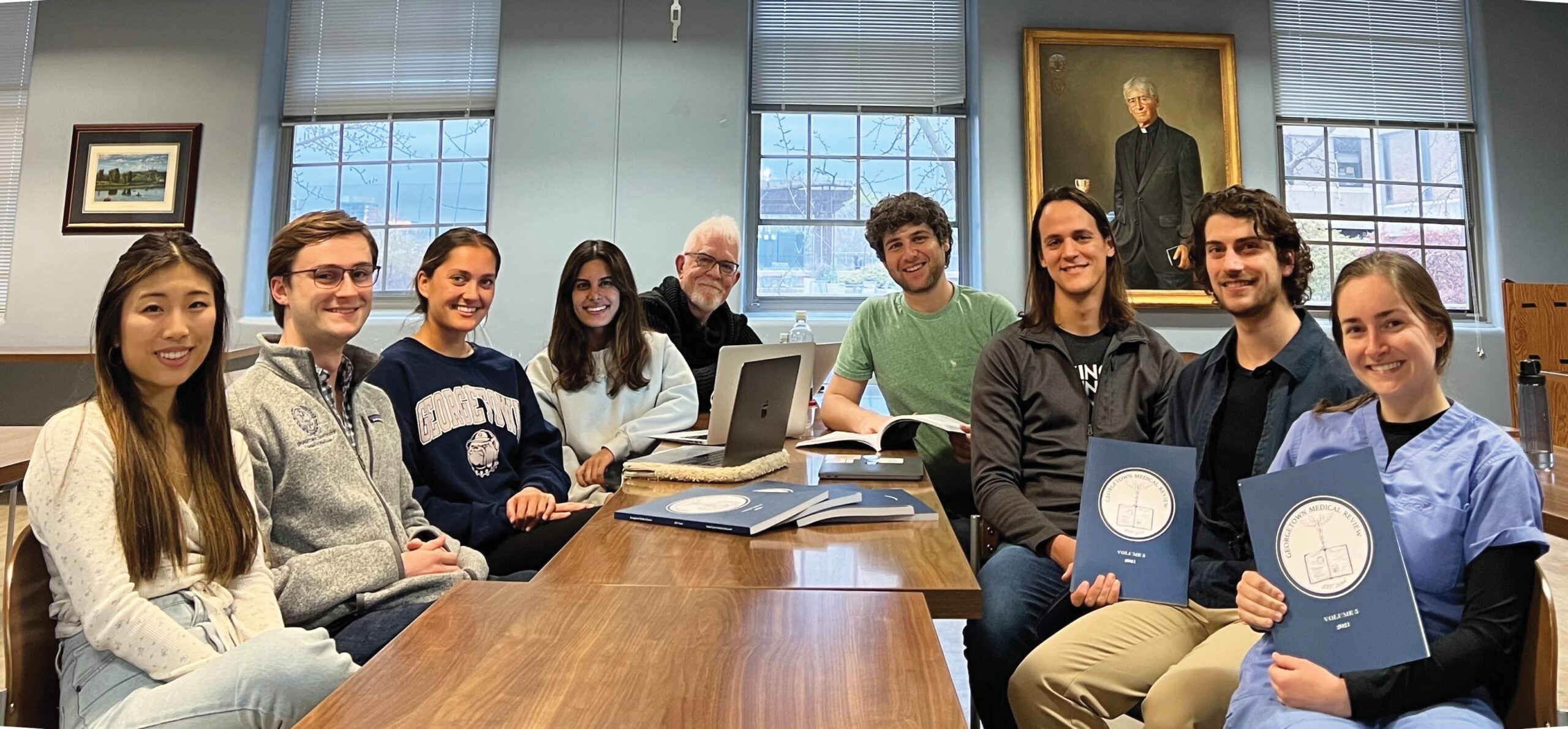 Georgetown Medical Review students and Michael Plankey, journal co-founder and current publisher, gather together while sharing printed copies of the journal.