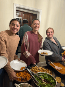 three people smiling at the camera in front of a buffet