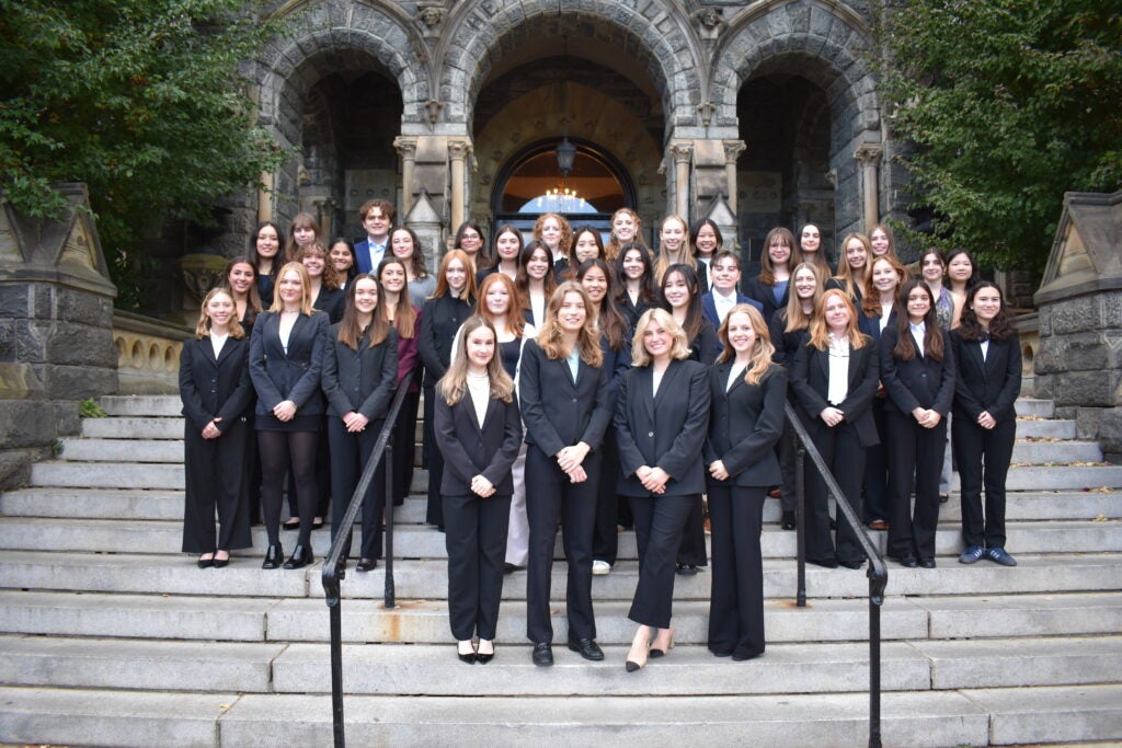 a group of people in business attire stand on the steps outside Healy Hall 