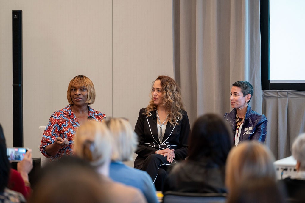 three women sit in front of a room of people
