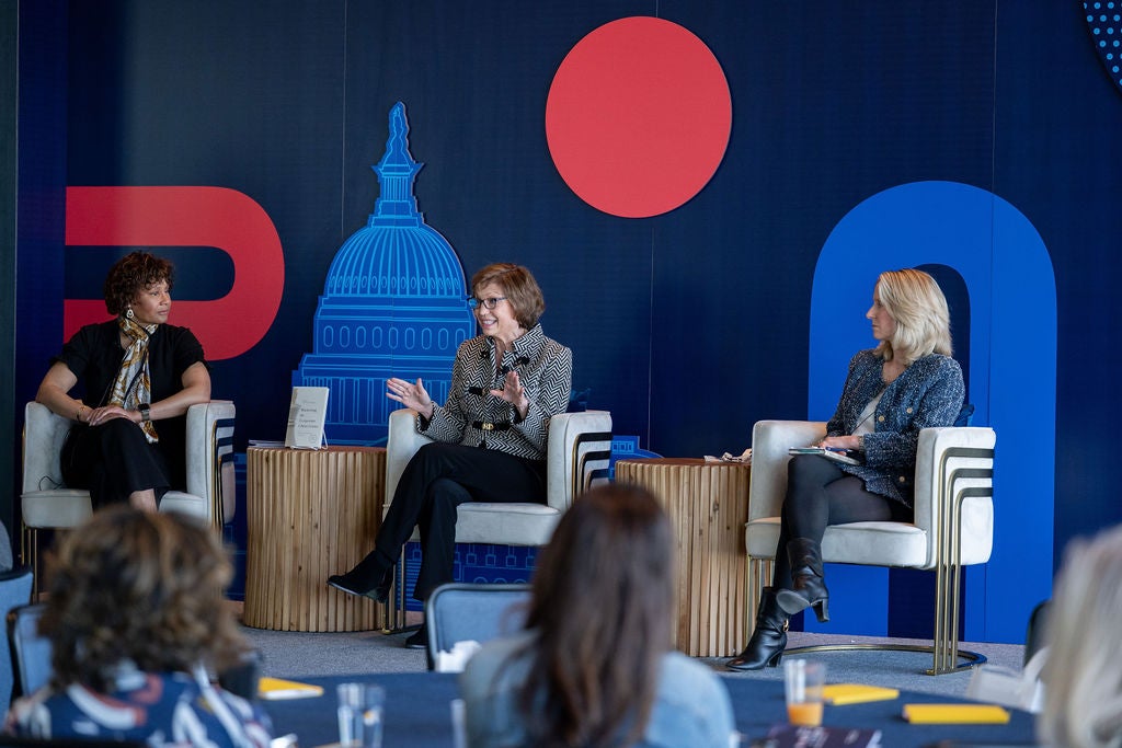 three women in chairs on a stage in front of a room full of people