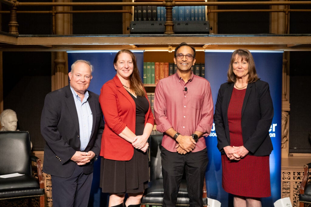 four people stand on a stage in a library 