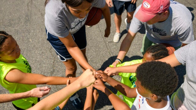 people putting hands into middle in a group