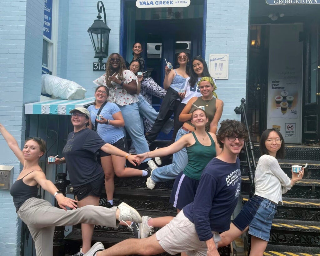 a group of students strike a ballet pose on the front steps outside a cafe