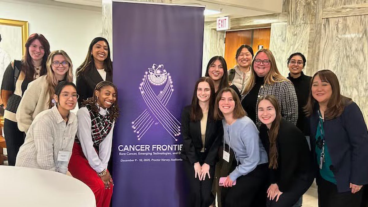 Students and Professor Tomoko Steen (right) stand around the banner for the Cancer Frontiers symposium. | Photo: Courtesy of Biomedical Graduate Education