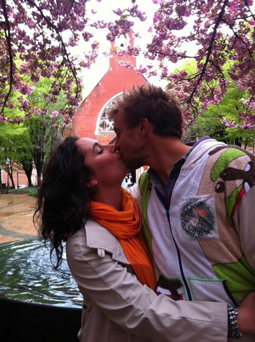 Giulia and Mark kiss in Dahlgren Quad under a blossoming tree.